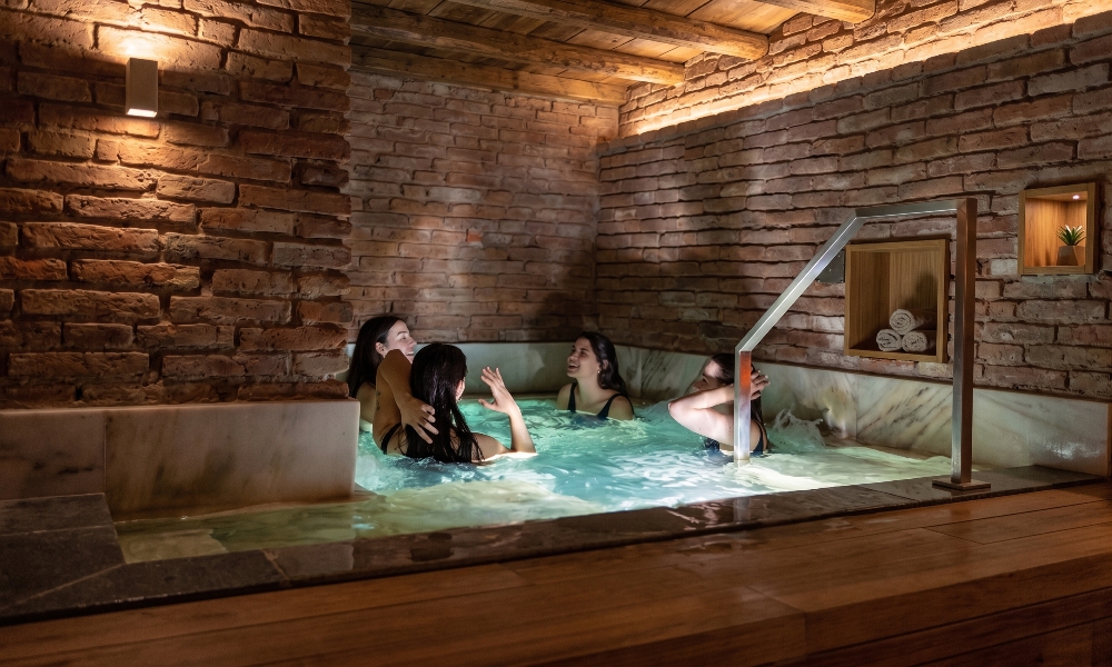 Amigas relajándose en las cálidas aguas del circuito subterráneo de los Baños de Azur, reconocido como el mejor SPA en Córdoba.